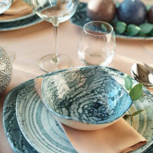 Beautiful elegant table setting with green stylish dishware and silver cutlery close up
