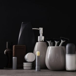 Bottles and jars with men's cosmetics and towel on black background