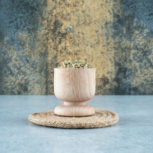 Green anise seeds in a wooden cup on blue background. High quality photo